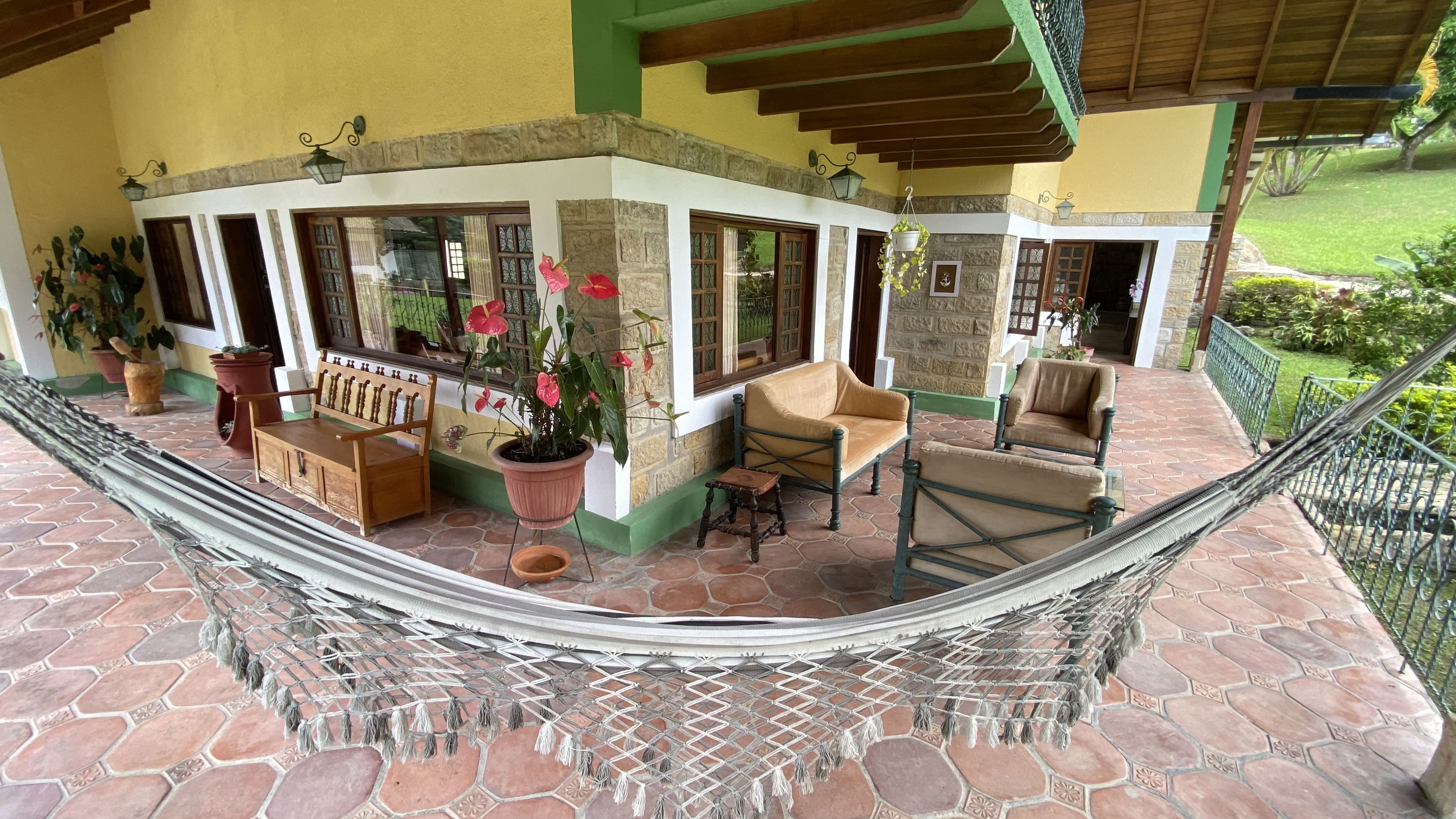 Corredor de una finca con hamaca, plantas y vista al jardín